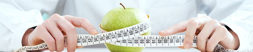 Das Mädchen misst den Apfel mit einem Zentimeterband